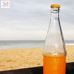 Bottle of orange juice on the beach