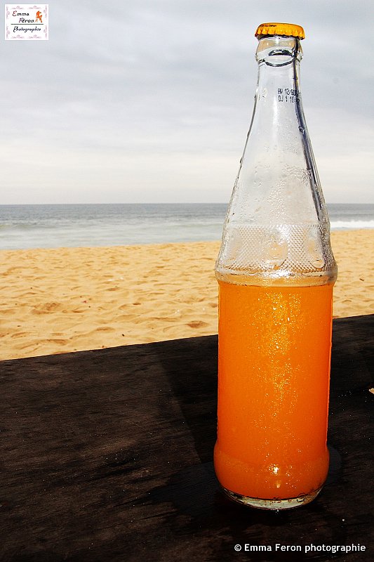 Bottle of orange juice on the beach